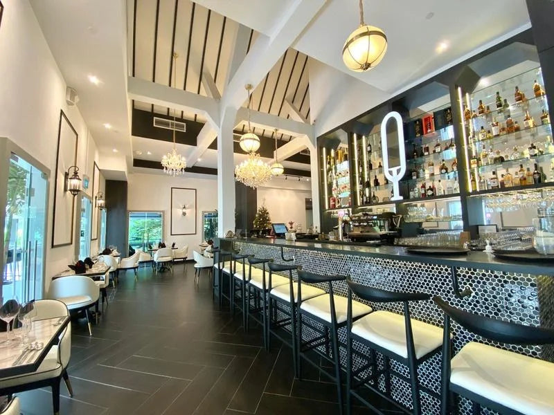 Indoor dining area at Quentin’s Sentosa with chandeliers and bar seating